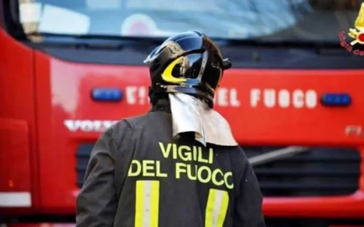 Vigili del fuoco di spalle davanti a un mezzo antincendio durante un intervento
