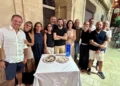 Gruppo di ex studenti riuniti attorno a un tavolo con due torte durante una cena a Modica