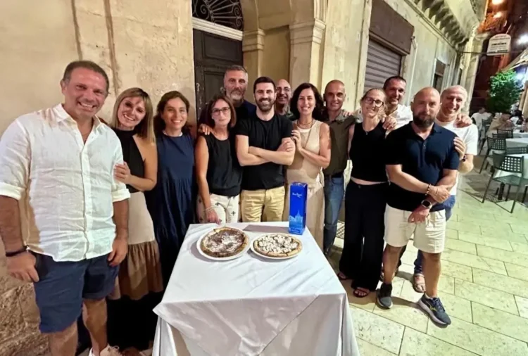 Gruppo di ex studenti riuniti attorno a un tavolo con due torte durante una cena a Modica