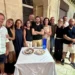 Gruppo di ex studenti riuniti attorno a un tavolo con due torte durante una cena a Modica