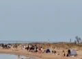 Decine di giovani sulla spiaggia di Playa Grande a Scicli al mattino, con tende ancora montate sulla battigia
