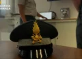 Berretto con fregio dorato della Guardia di Finanza su scrivania, militare in uniforme sullo sfondo