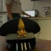 Berretto con fregio dorato della Guardia di Finanza su scrivania, militare in uniforme sullo sfondo