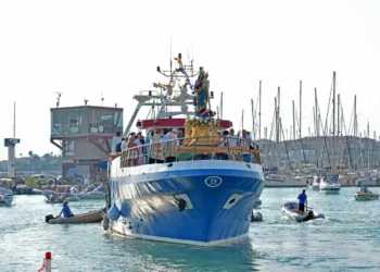 Il simulacro di Santa Maria di Portosalvo trasportato su un peschereccio blu nel porto di Marina di Ragusa, circondato da piccole imbarcazioni