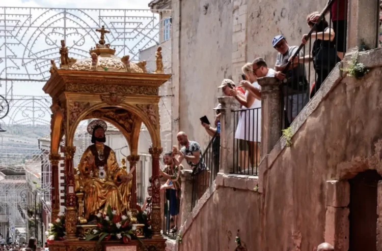 Simulacro dorato di San Bartolomeo in processione tra i vicoli, fedeli fotografano dai balconi