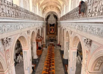 Interno barocco della chiesa madre di Monterosso Almo con matronei, lampadari e banchi in legno allineati verso l'altare