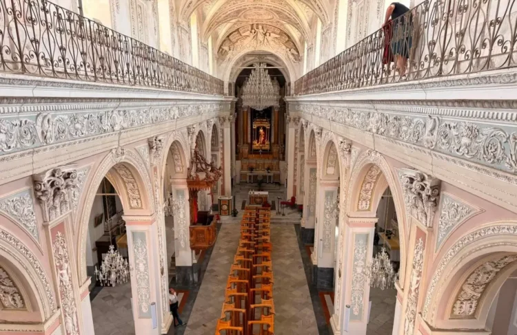 Interno barocco della chiesa madre di Monterosso Almo con matronei, lampadari e banchi in legno allineati verso l'altare