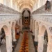 Interno barocco della chiesa madre di Monterosso Almo con matronei, lampadari e banchi in legno allineati verso l'altare