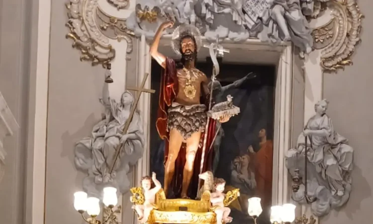 Statua di San Giovanni Battista nella nicchia dorata della cattedrale di Ragusa, con candelabri accesi alla base