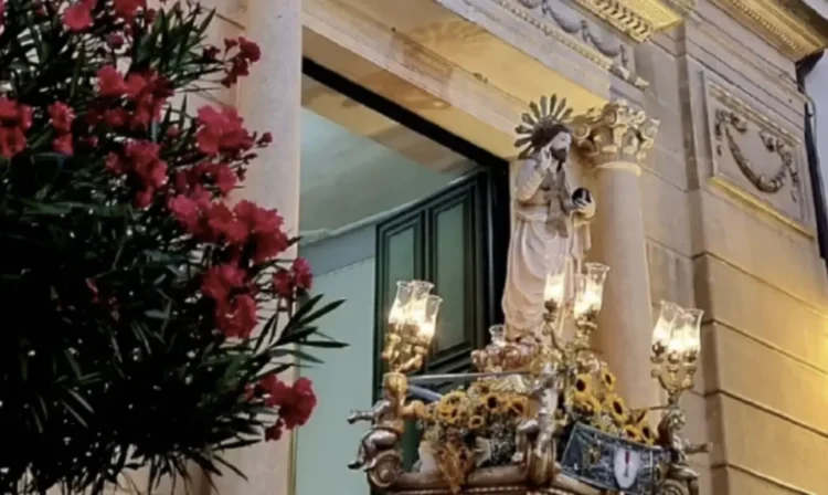 Il simulacro del Santissimo Salvatore su vara dorata con girasoli, illuminato da ceri, davanti alla facciata della chiesa madre di Chiaramonte Gulfi.
