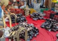 Bancarella con campanacci in metallo, finimenti in legno e cinghie di cuoio su un telo rosso al mercato