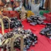 Bancarella con campanacci in metallo, finimenti in legno e cinghie di cuoio su un telo rosso al mercato