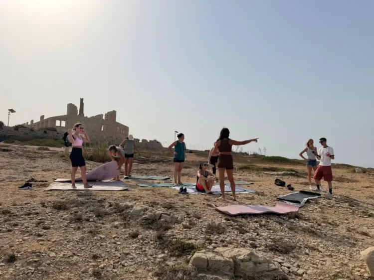 Gruppo di persone con tappetini da yoga davanti alla Fornace di Punta Pisciotto a Sampieri, durante le riprese di Rai Uno.