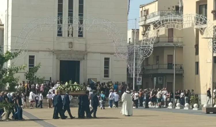 Feretro con fiori bianchi portato in piazza davanti alla chiesa di Santa Maria di Portosalvo a Scoglitti
