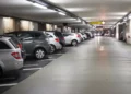 Auto parcheggiate in un parcheggio multipiano coperto, con corsia centrale e posti auto su entrambi i lati.