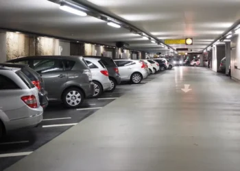 Auto parcheggiate in un parcheggio multipiano coperto, con corsia centrale e posti auto su entrambi i lati.