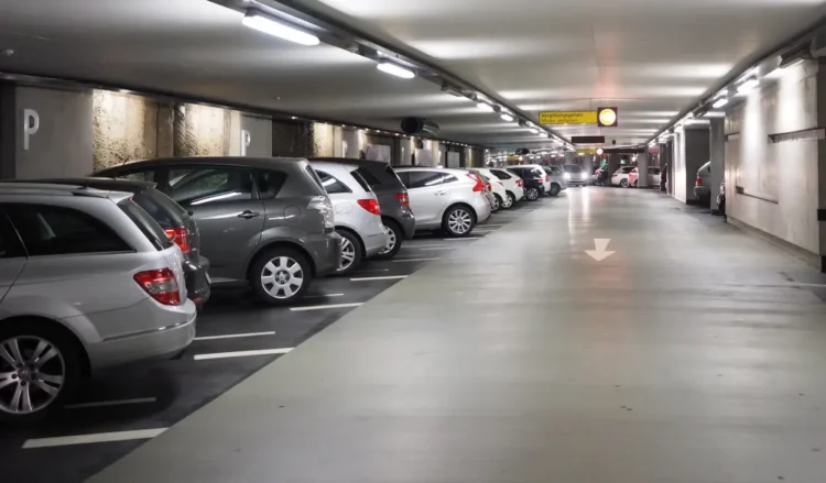 Auto parcheggiate in un parcheggio multipiano coperto, con corsia centrale e posti auto su entrambi i lati.