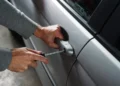Mani con un cacciavite forzano la serratura dello sportello di un'auto in sosta.
