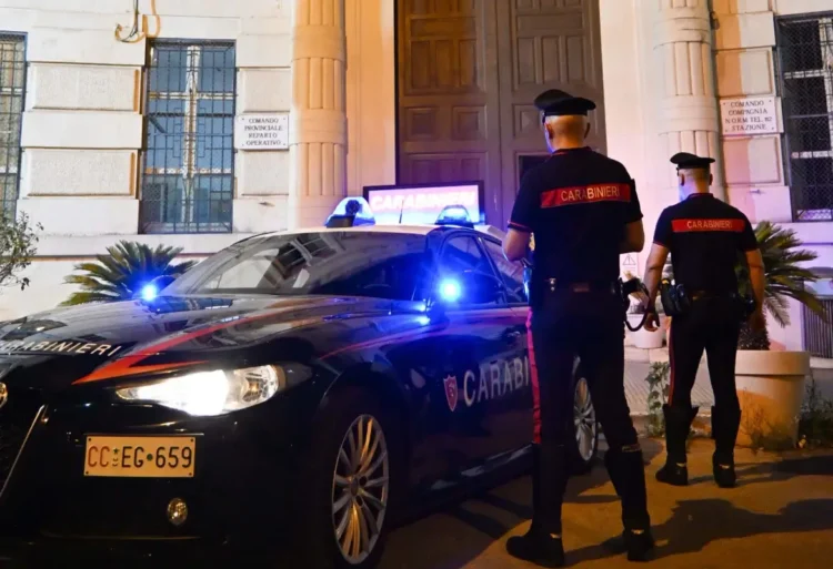 Pattuglia dei Carabinieri e due militari davanti alla caserma durante un servizio notturno