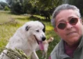 Giovanna Cicero Molè in un selfie all'aperto con un cane bianco, tra alberi e campagna verde.