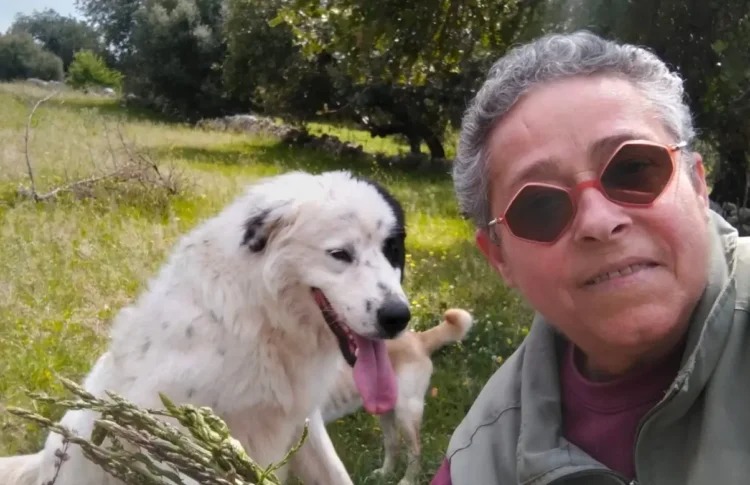 Giovanna Cicero Molè in un selfie all'aperto con un cane bianco, tra alberi e campagna verde.