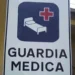 Cartello stradale bianco con scritta "Guardia Medica" e simbolo di letto ospedaliero con croce rossa su sfondo blu