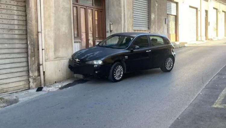 Auto scura ferma contro un muro in una strada di Modica