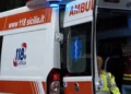 Ambulanza del 118 Sicilia con portiere posteriori aperte e operatrice sanitaria in giubbotto giallo fluorescente.
