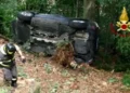 Vigile del fuoco a fianco di un'auto rovesciata sul fianco in una scarpata
