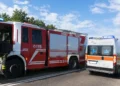 Autopompa dei vigili del fuoco e ambulanza del 118 fermi sul bordo di una strada durante un intervento di soccorso