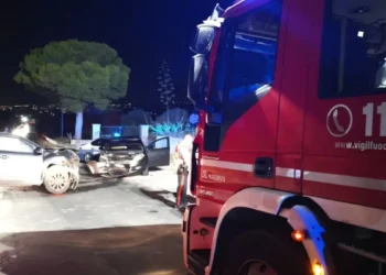 Due auto schiacciate dopo uno scontro frontale, con un mezzo dei Vigili del Fuoco sul posto di notte.