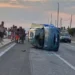 Fiat 600 rovesciata sul fianco sulla SP67 tra Marza e Pozzallo, con ambulanza e passanti sullo sfondo al tramonto