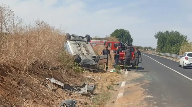 Auto ribaltata tra la vegetazione a bordo strada, vigili del fuoco accanto al mezzo dei pompieri