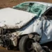 Auto bianca con il muso distrutto e il parabrezza sfondato dopo un incidente stradale.