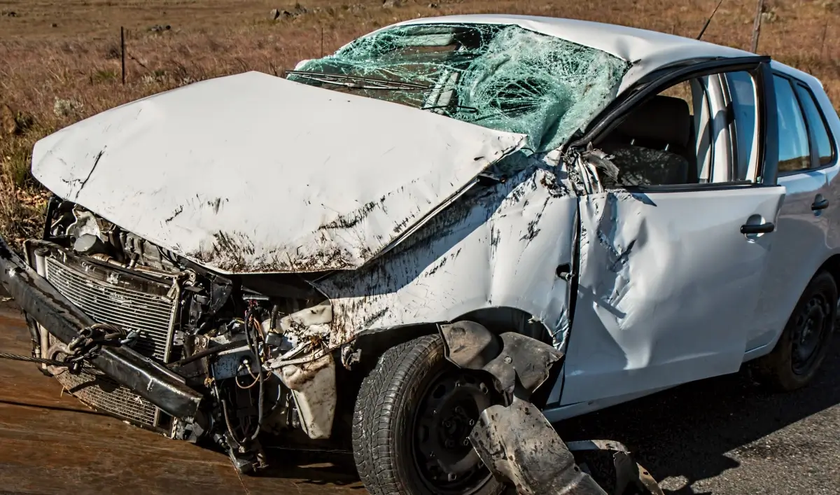 Auto bianca con il muso distrutto e il parabrezza sfondato dopo un incidente stradale.