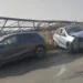 Suv scuro e utilitaria bianca con il muso danneggiato, ferme sull'asfalto dopo lo scontro, sullo sfondo una tettoia agricola.