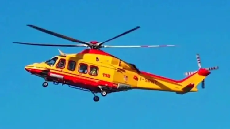 Elicottero del servizio di elisoccorso in volo su cielo azzurro, livrea gialla e rossa con scritta 118