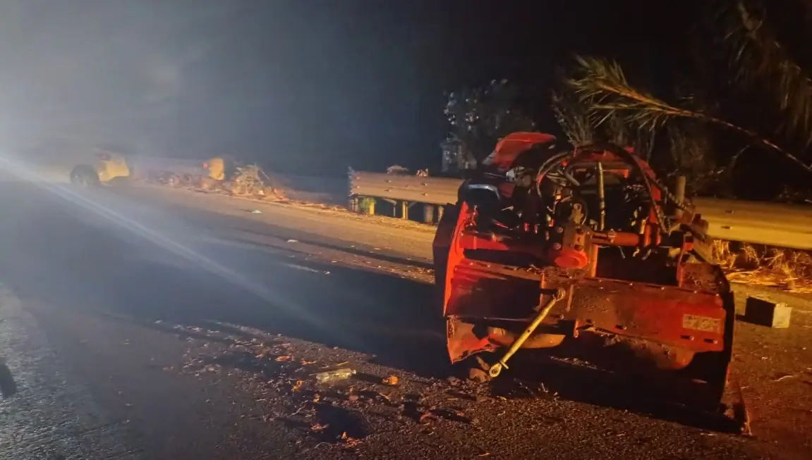 Veicolo gravemente danneggiato dopo un incidente notturno, fermo accanto al guardrail con detriti sulla carreggiata