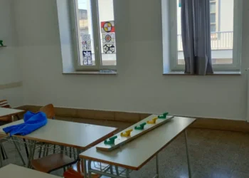 Aula scolastica vuota con banchi, sedie e finestre con vetri colorati durante i lavori estivi di manutenzione