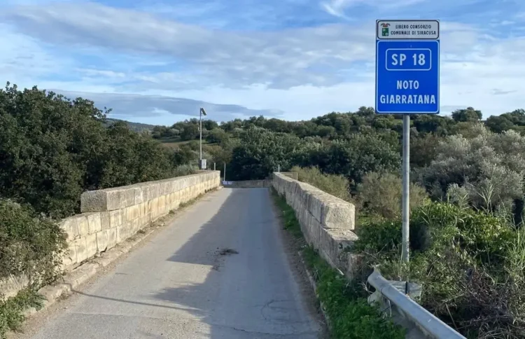 Cartello della SP18 Noto Giarratana su un ponte immerso nella campagna