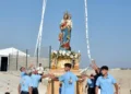 Fedeli in maglietta azzurra sistemano con nastri il simulacro della Madonna di Portosalvo sul fercolo dorato, all'aperto.