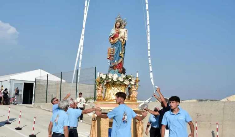 Fedeli in maglietta azzurra sistemano con nastri il simulacro della Madonna di Portosalvo sul fercolo dorato, all'aperto.