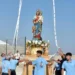 Fedeli in maglietta azzurra sistemano con nastri il simulacro della Madonna di Portosalvo sul fercolo dorato, all'aperto.