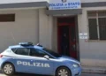 Auto della Polizia di Stato parcheggiata davanti all'ingresso di un commissariato con insegna sulla facciata