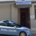 Auto della Polizia di Stato parcheggiata davanti all'ingresso di un commissariato con insegna sulla facciata