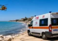 Ambulanza del 118 e elicottero di soccorso sulla spiaggia, con il mare sullo sfondo.