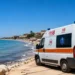 Ambulanza del 118 e elicottero di soccorso sulla spiaggia, con il mare sullo sfondo.