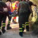 Vigili del fuoco trasportano su barella una persona soccorsa in un sentiero scosceso tra la vegetazione.