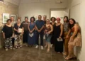 Gruppo di allievi e organizzatori posa nella sala della Fondazione Confeserfidi a Scicli, con quadri esposti alle pareti.