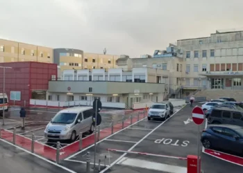 Parcheggio e ingresso dell'ospedale Guzzardi di Vittoria con ambulanza in sosta, ripreso in una giornata nuvolosa